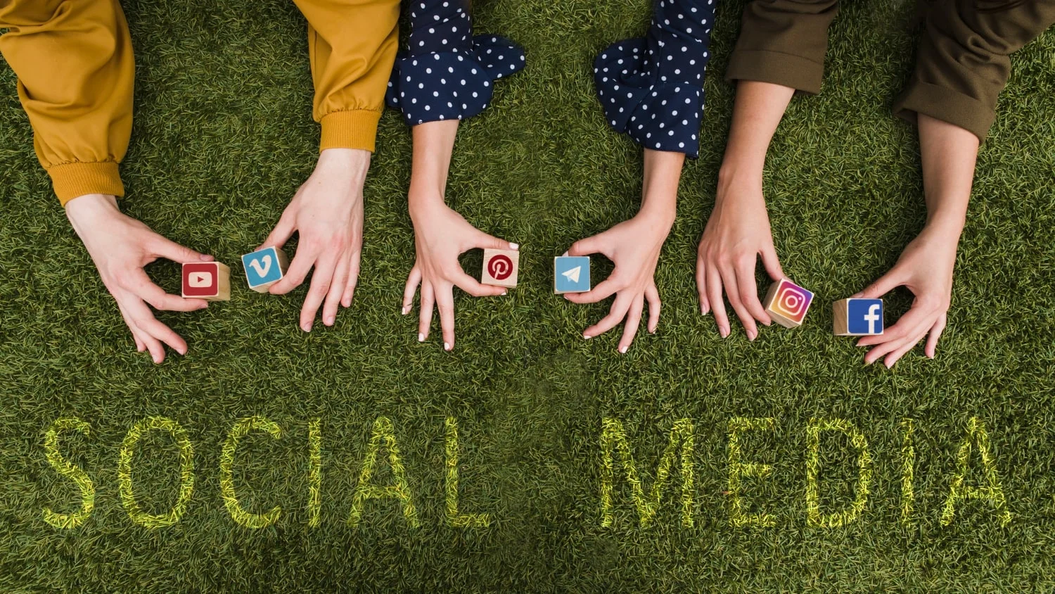 Free photo overhead view of female's hand holding social network app symbol blocks on lawn